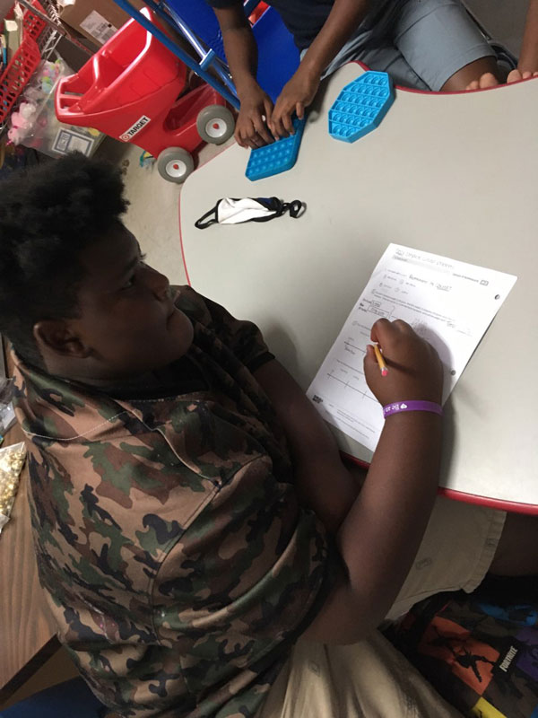 Boy focusing on writing in a workbook.