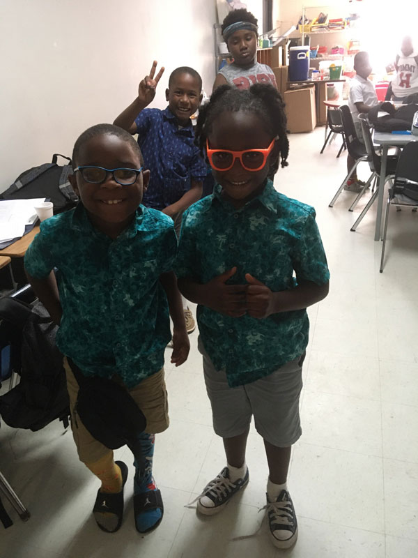 Three children in matching shirts giving peace signs.