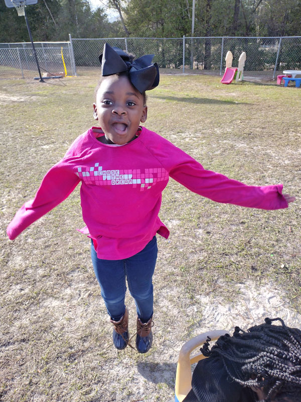 Happy child with arms outstretched and mouth open.