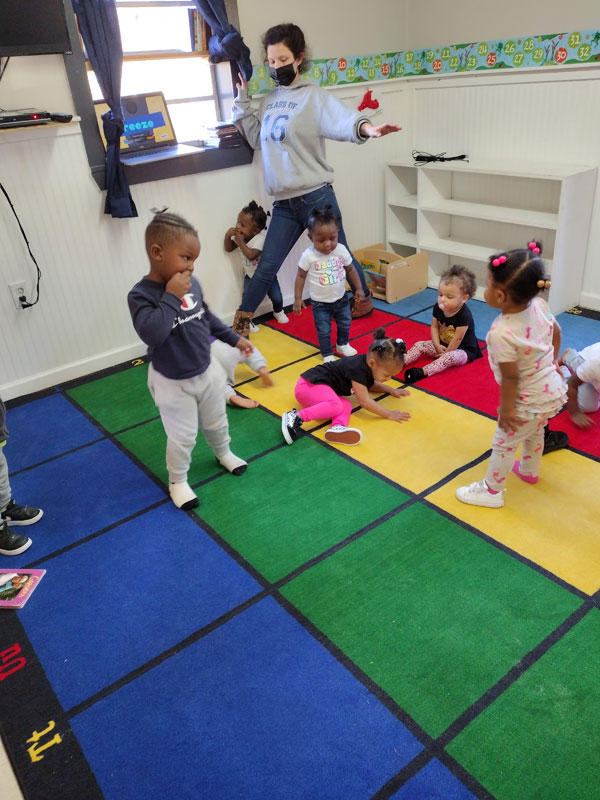 Adult and children dancing on a colorful mat.