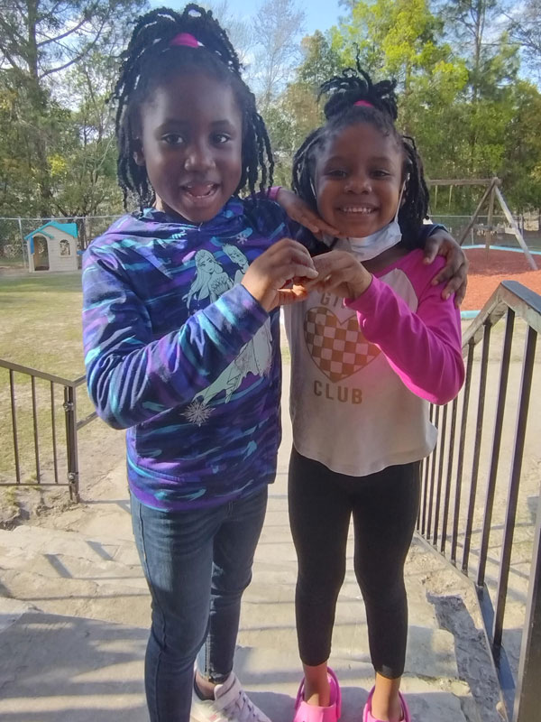 Smiling girls holding hands on a playground.