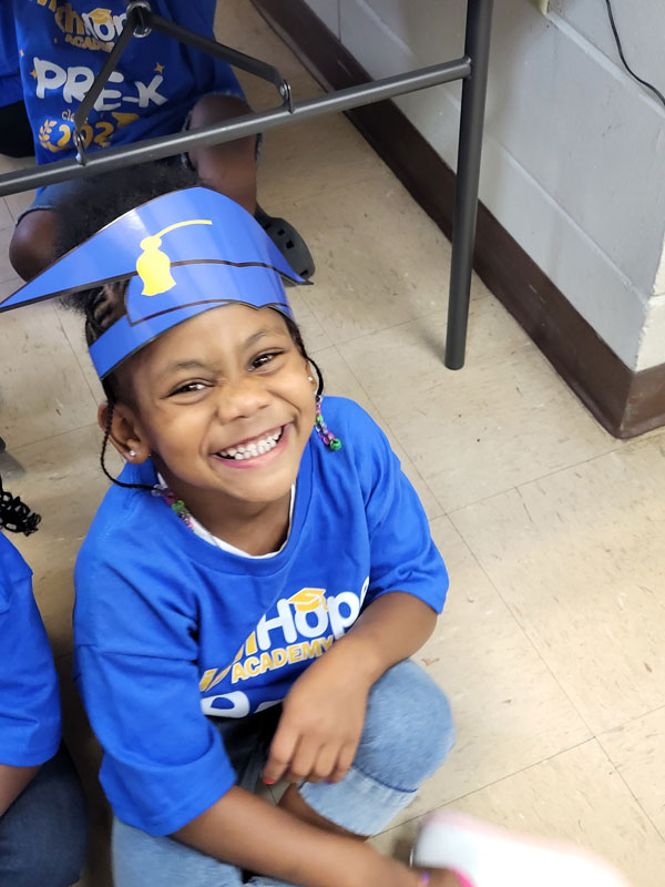 Happy child in a graduation cap laughing joyfully.