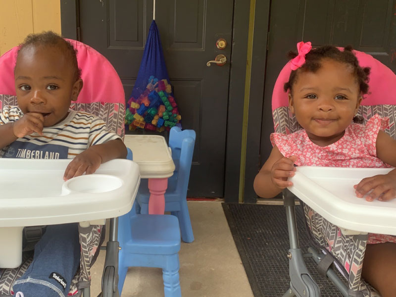 Two children at high chairs smiling.