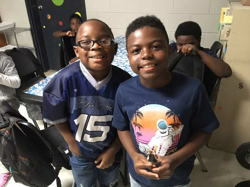 Boys in jerseys smiling with backpacks.