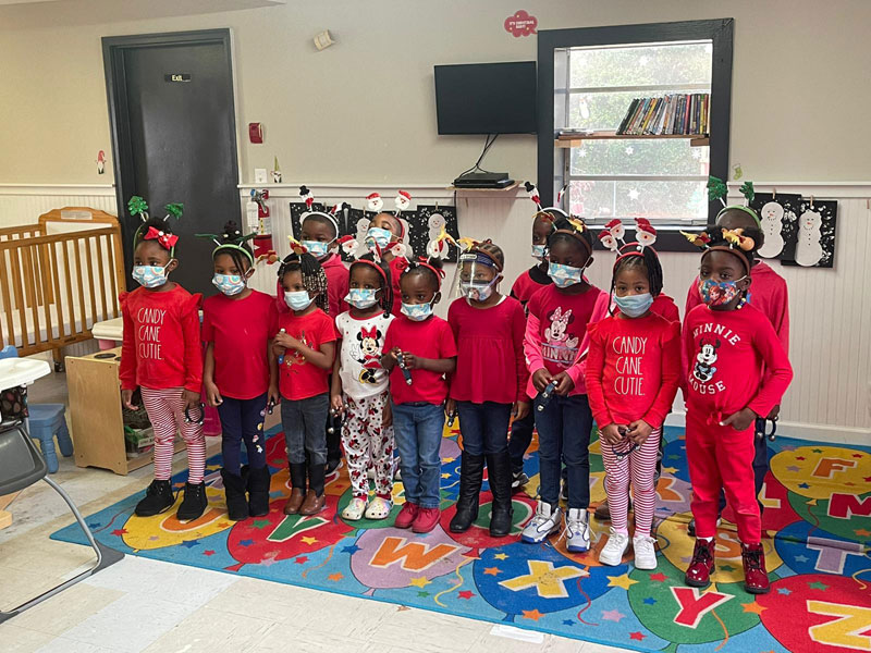 Children in red outfits with holiday decorations.