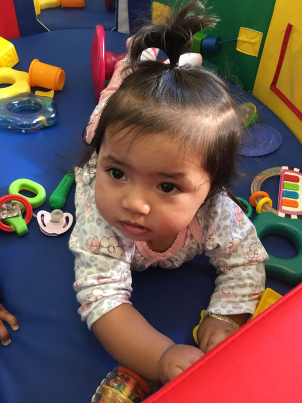 Toddler playing with colorful toys on a blue mat.