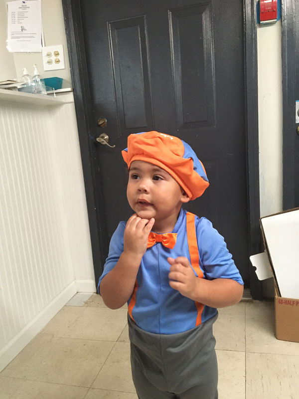 Child in an orange chef hat with a thoughtful expression.