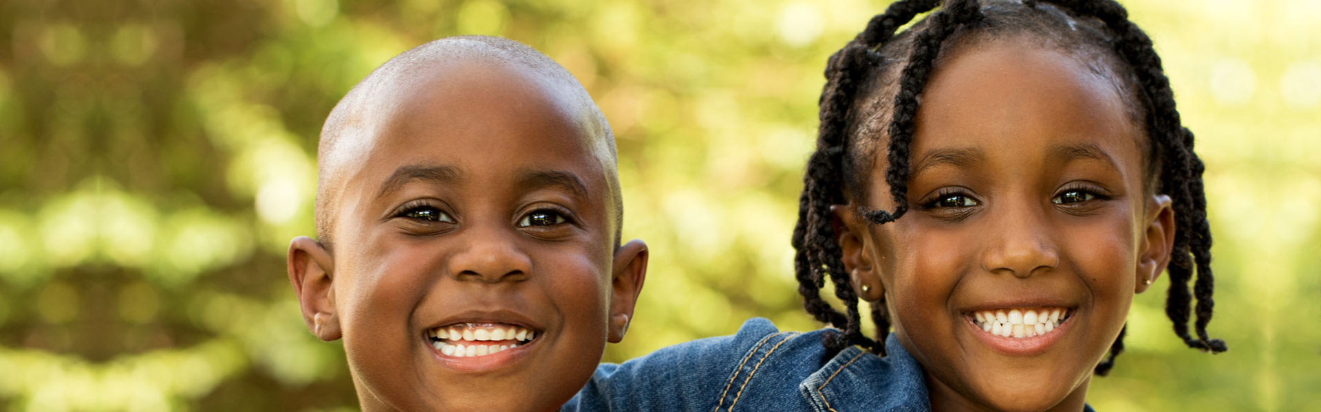 Close-up of two smiling children in nature.